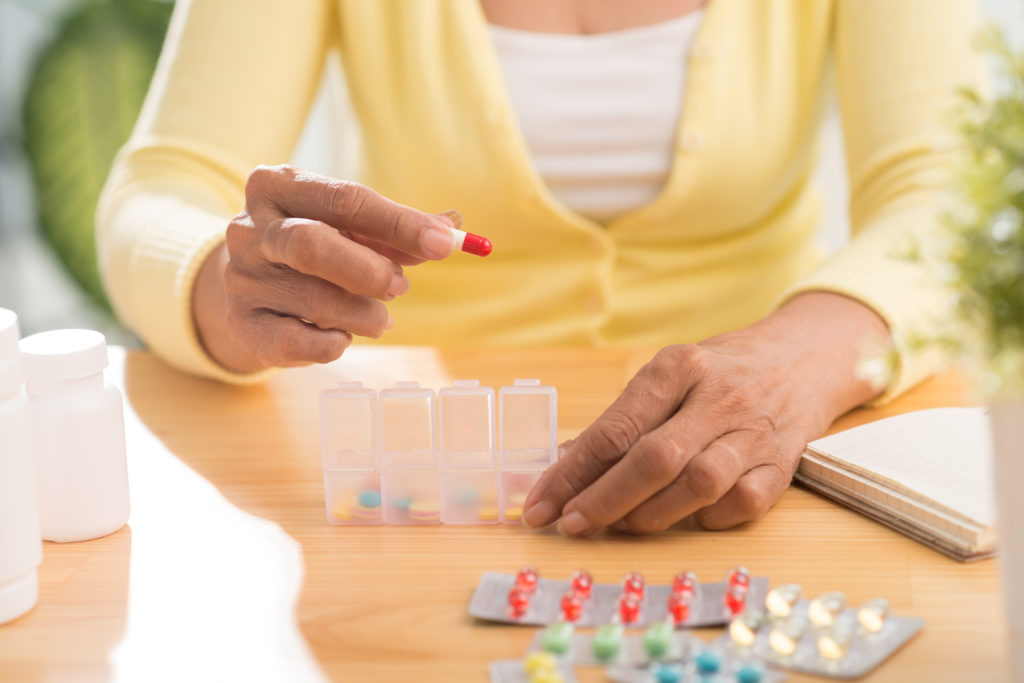 Woman putting weekly medications in an organizing container.